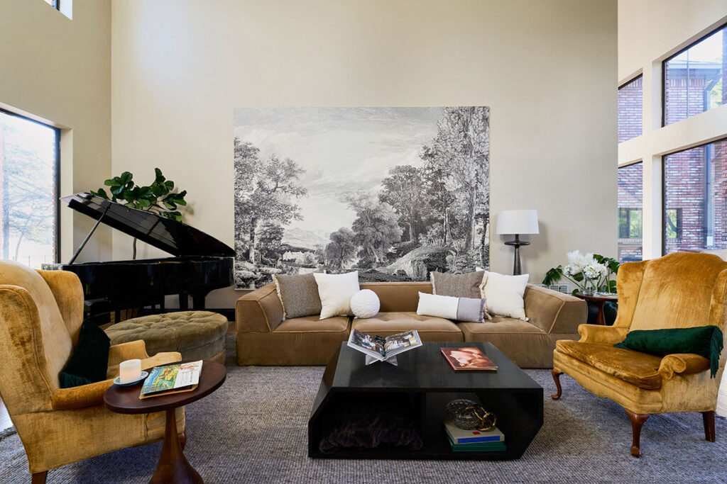 Large living room with gold upholstered seating, baby grand piano, and modern black coffee table
