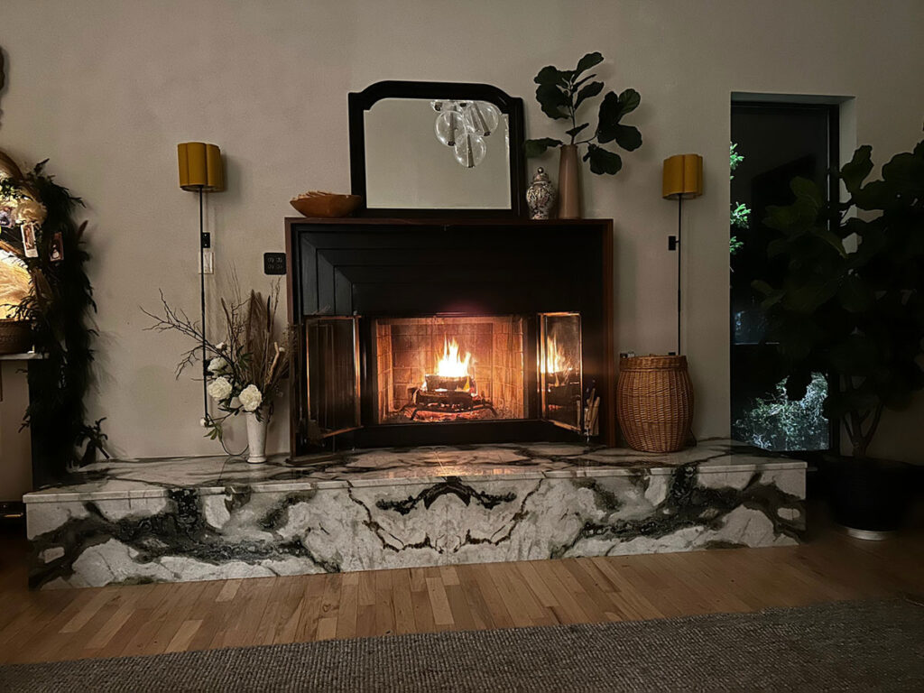 Lit fireplace with ipe wood mantle and marble platform
